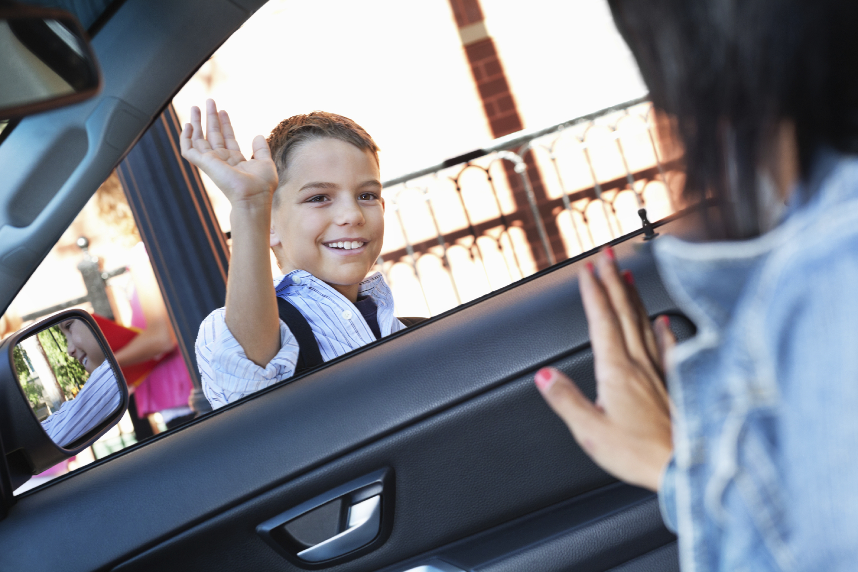 Boy waving at parent school zone drop off